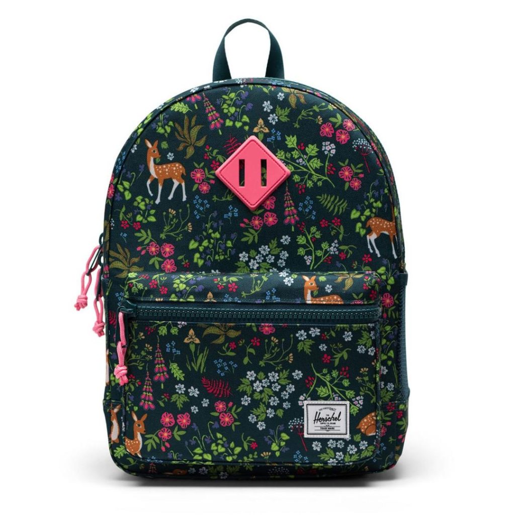 small backpack with an allover print featuring brown and white deer, branches with leaves in different shades of green, colourful pink and blue flowers against a midnight blue/navy background; the bag includes a contrast pink Herschel diamond logo patch at the front and a carry handle at the top, as well as contrast pink zipper pulls, a zippered front pocket with a small white Herschel logo patch at the front-left bottom side