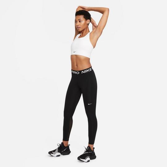 female model stretching her arms over her head, wearing a white Nike sports bra and black Nike Pro leggings with contrast white Nike branding along the waistband and a contrast white Nike Swoosh logo at the right left thigh, along with black Nike athletic shoes with contrast hits of white and grey; gym class essentials